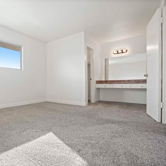 a room with a carpet, a window, and a mirror.
