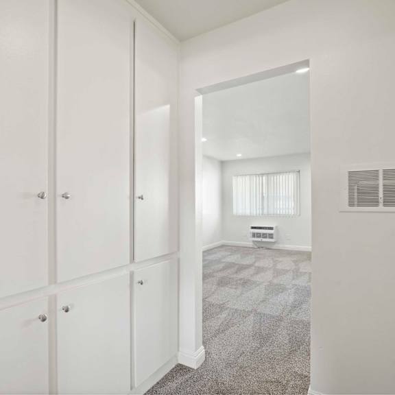 a white hallway with a carpeted floor and a white door on the right.