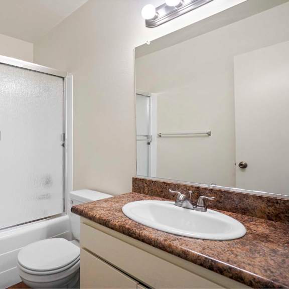 a bathroom with a toilet, sink, and shower.