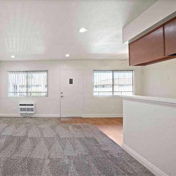 a spacious room with a grey carpet and white walls.