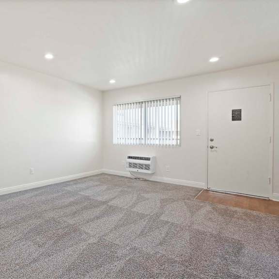 a room with a carpeted floor and a window with blinds.