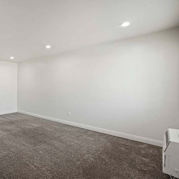 a room with a grey carpet and a white wall.