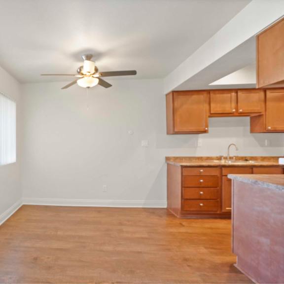 a room with a ceiling fan and a kitchenette.