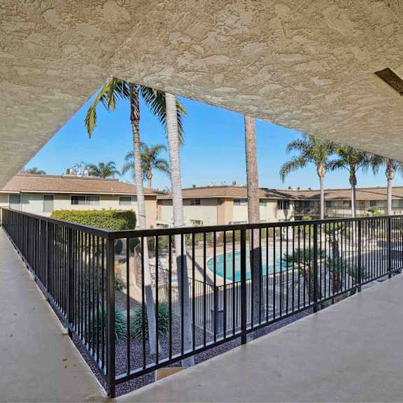 a balcony with a black railing and a pool in the background.