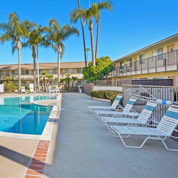 a pool surrounded by chairs and palm trees.