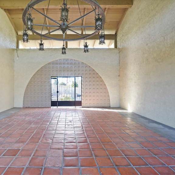 a large room with a brick floor and a circular chandelier hanging from the ceiling.
