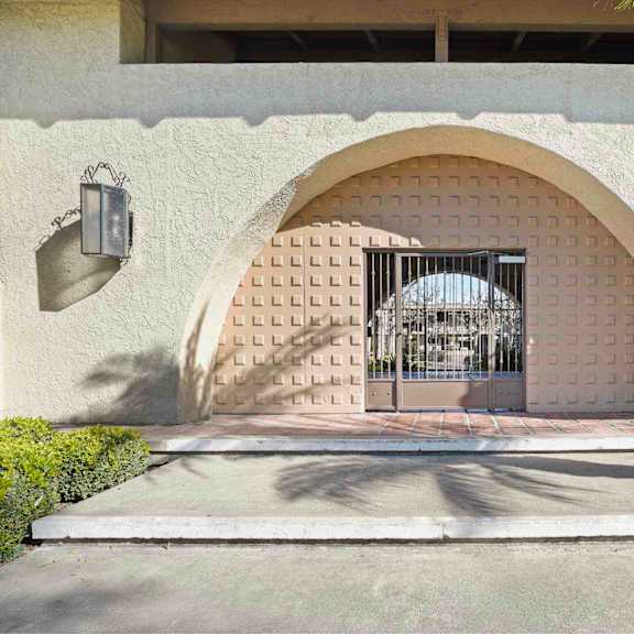 a white building with a gate and a palm tree in front.