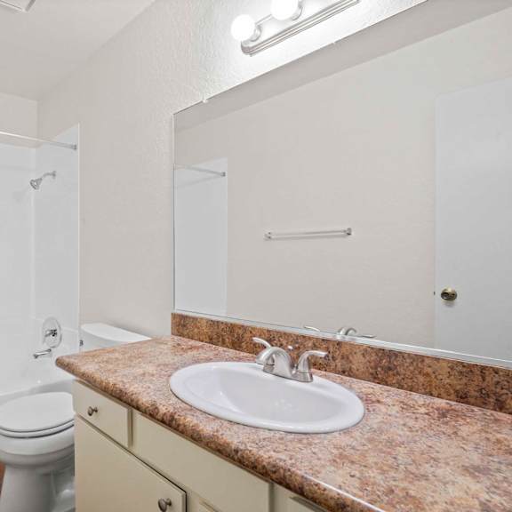 a bathroom with a sink, toilet, and mirror.
