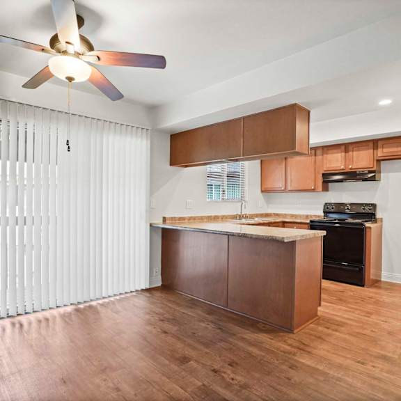 a kitchen with a wooden floor and a ceiling fan.