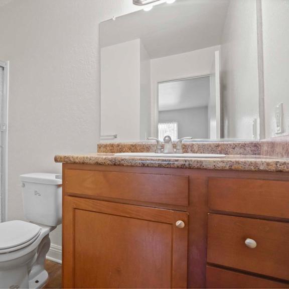 a white toilet sits next to a white fridge in a bathroom.