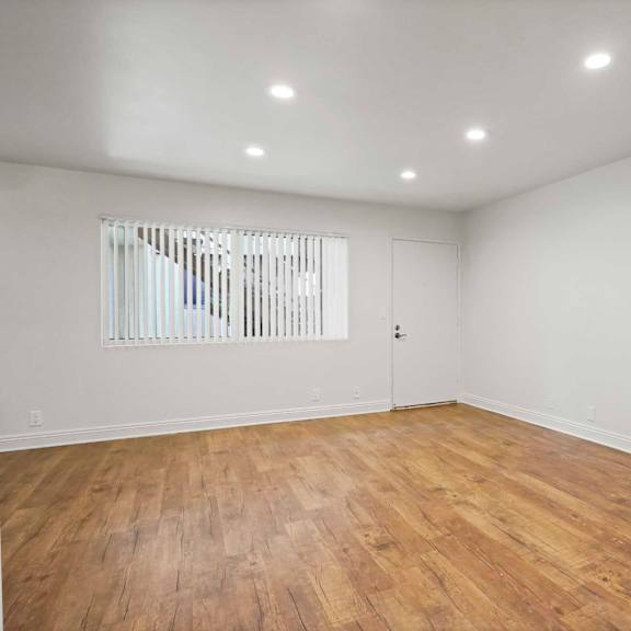 a room with wooden flooring and a window with blinds.