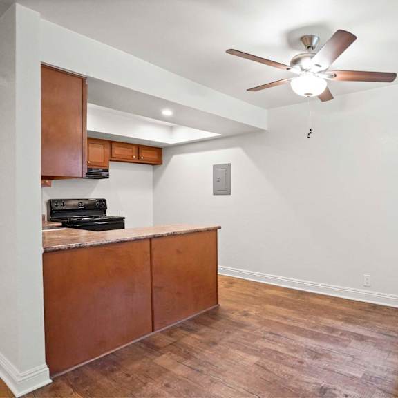 a room with a ceiling fan and wooden flooring.