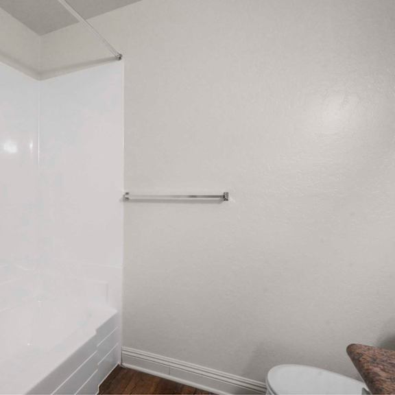 a white bathroom with a toilet and a towel bar.