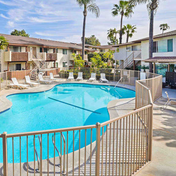 a pool surrounded by a fence and chairs.