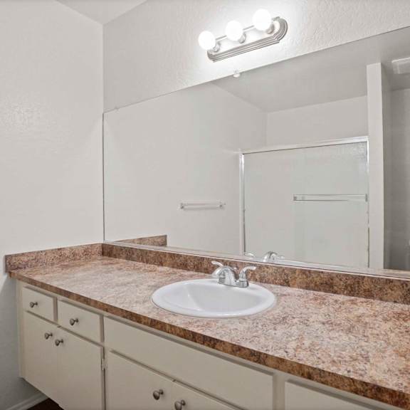 a bathroom with a sink, mirror, and cabinets.