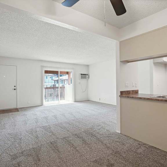 a spacious room with a carpeted floor and a window overlooking a deck.