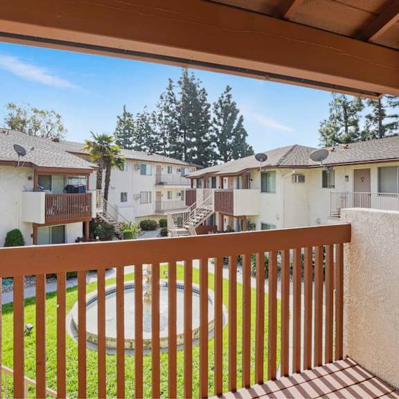 a view from a balcony overlooking a grassy area and apartment buildings.