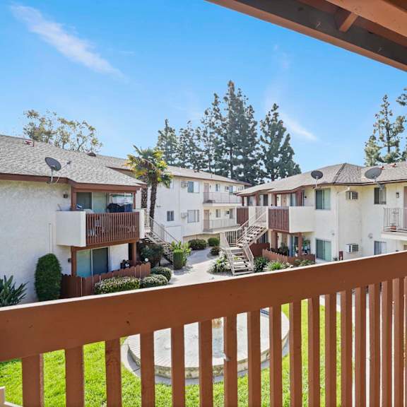 a view from a balcony overlooking a courtyard with a grassy area and apartment buildings.