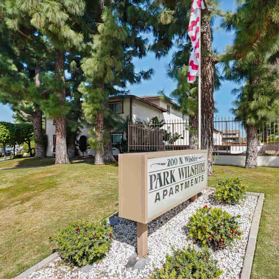 a sign for park wilshire apartments is in front of a building and trees.