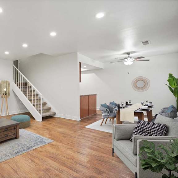 a living room with a staircase and a dining area.
