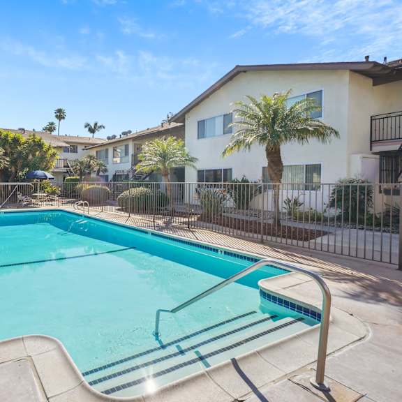 a swimming pool surrounded by a fence and palm trees.