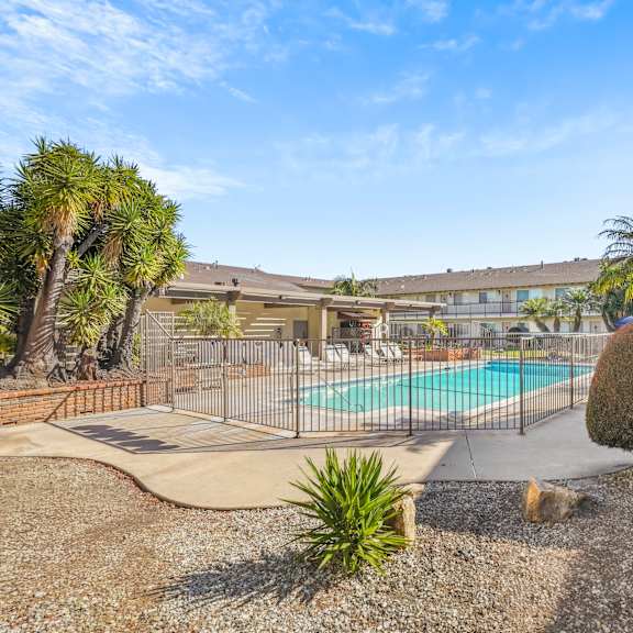 a pool surrounded by a fence and a few trees.