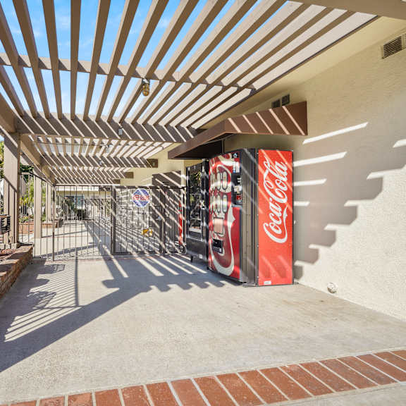a coca cola machine is under a wooden canopy.