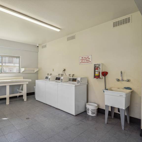 a clean, white medical room with a table, sinks, and a window.