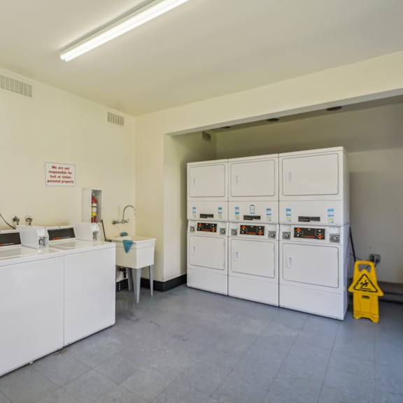 a clean, white room with a yellow caution sign and a white cabinet with a door.