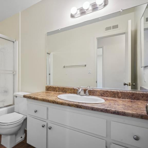 a white bathroom with a toilet, sink, and mirror.