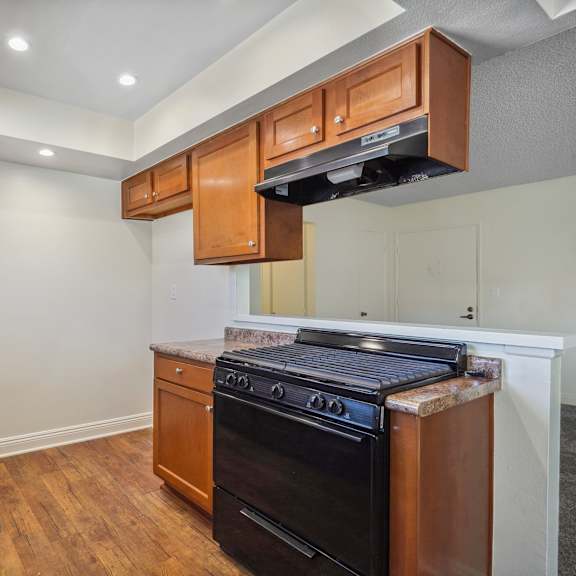 a kitchen with a black oven and wooden cabinets.