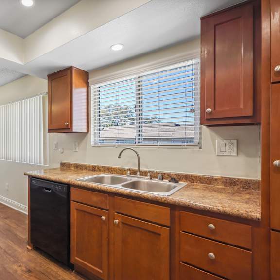 a kitchen with wooden cabinets and a black dishwasher.