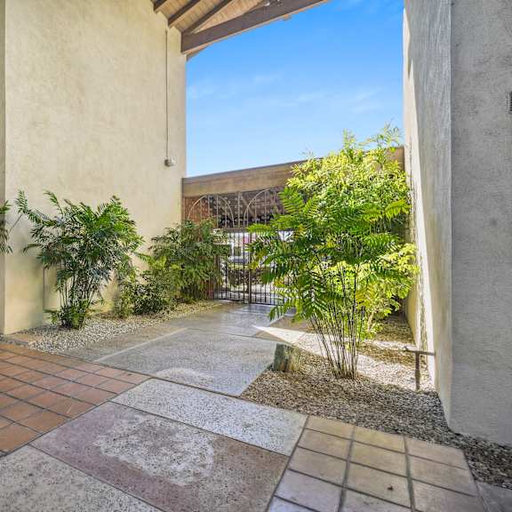 a patio area with a tiled floor and a variety of plants.