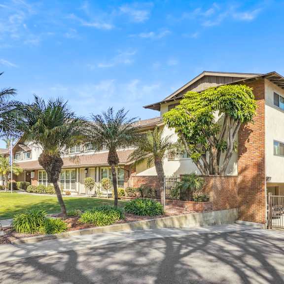 a building with a driveway and palm trees in front.