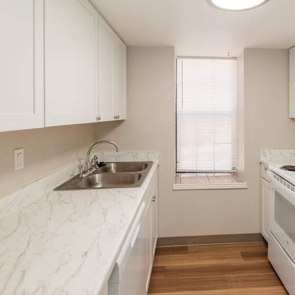 a white kitchen with a sink, stove, and refrigerator.