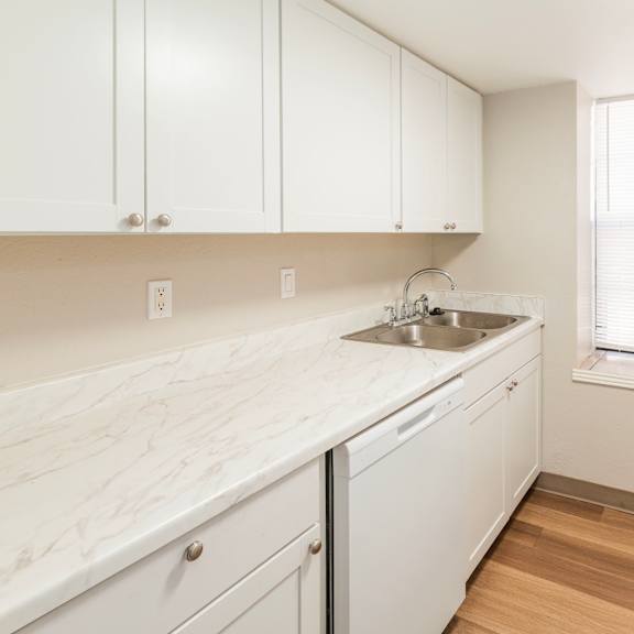 a kitchen with white cabinets and a marble countertop.