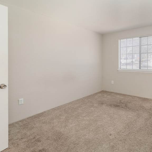 a room with a carpeted floor and a window with blinds.