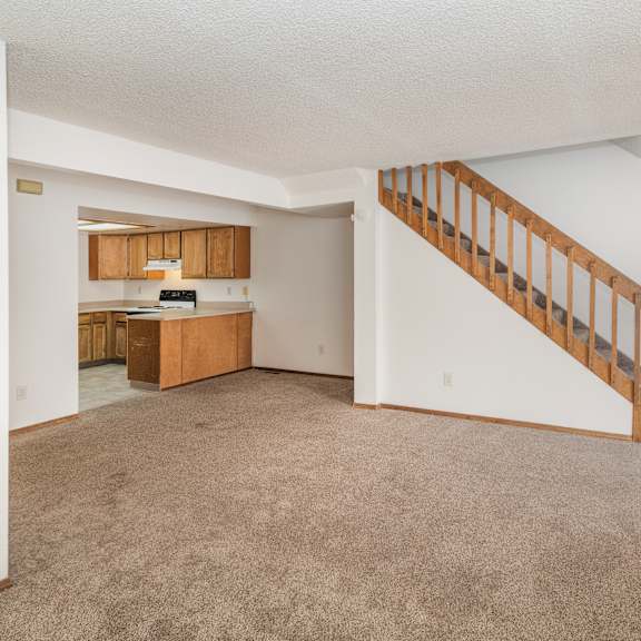 a spacious living room with a staircase leading to the upper floor.