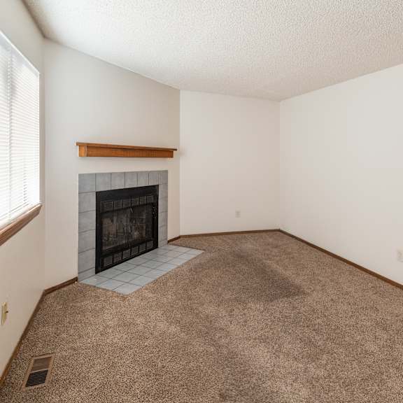 a living room with a fireplace and carpeted floor.