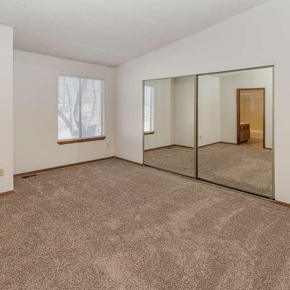 a large empty room with a carpeted floor and a large mirror on the wall.