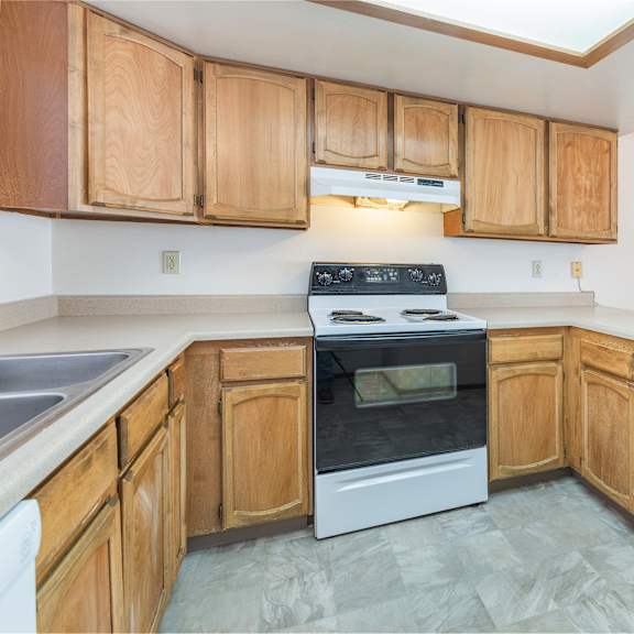 a kitchen with wooden cabinets and a white stove top oven.