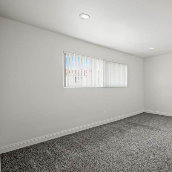 a room with a carpeted floor and a window with blinds.