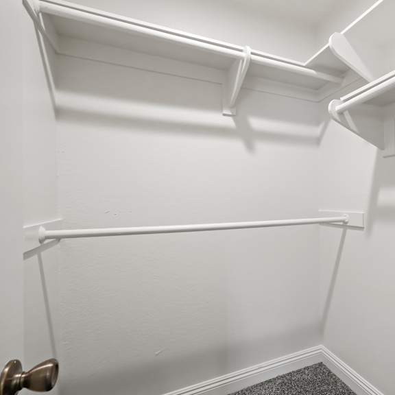 a white closet with a door and a shelf.