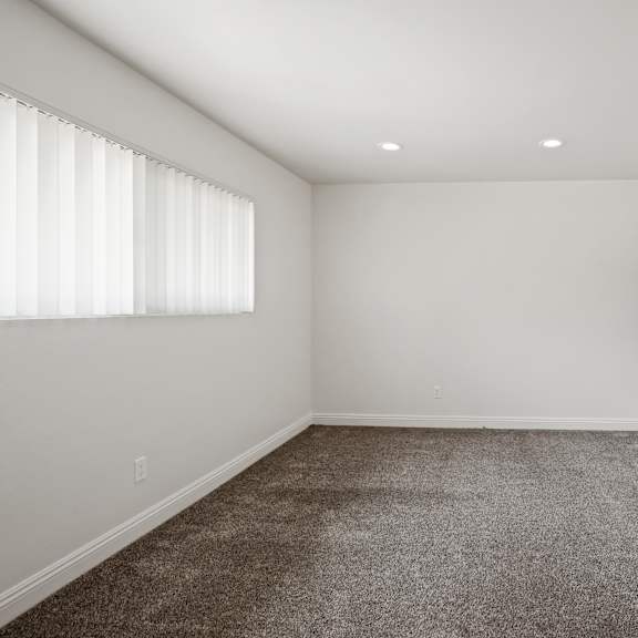 a room with a carpeted floor and a window with blinds.