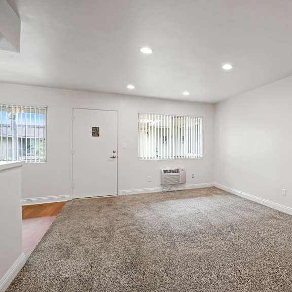 a room with a carpeted floor and a window with blinds.