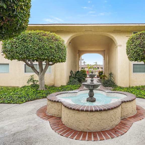 a fountain in the middle of a courtyard surrounded by trees.