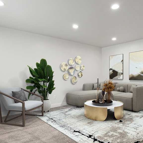 a living room with a grey couch, a round coffee table, and a plant.