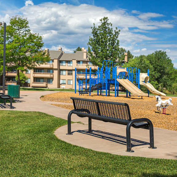 a playground with a slide and a bench in the foreground.