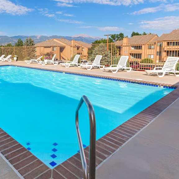 a swimming pool with a ladder and sun loungers.