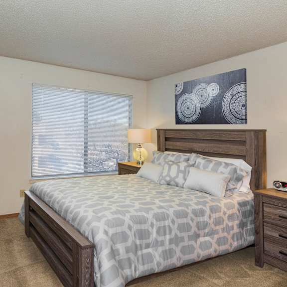 a bedroom with a large bed, a nightstand, and a potted plant.